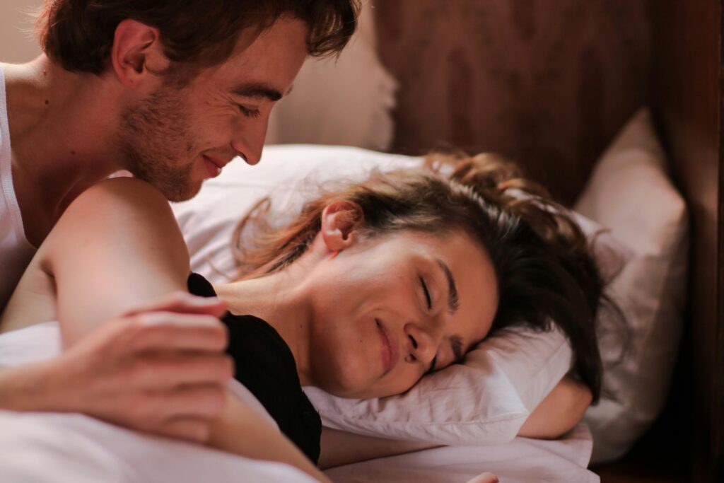 Intimate moment of a couple cuddling in bed, showcasing warmth and affection.